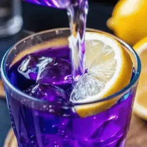 Butterfly Pea Flowers – Iced tea with blue hue in a tall glass, garnished with mint and edible flowers.