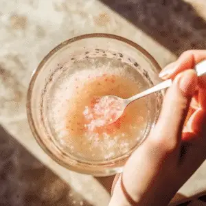 Pink Salt Trick Recipe – A small spoon of pink Himalayan salt beside a glass of lemon-infused water.