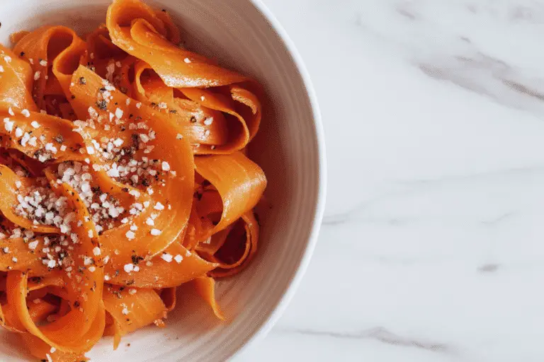 Ribbon Carrot Salad with fresh herbs and sesame seeds served on a grey plate.
